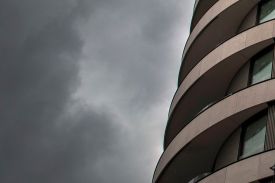 An up-close portion of the Riverwalk apartment building is pictured as gray clouds loom to the left.