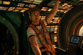 A man wearing a harness floats in a spacecraft.