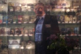 A person is seen through a wall of photographs of prisoners at a former KGB prison.