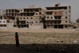 A boy walks past destroyed buildings in Ghouta, Syria.