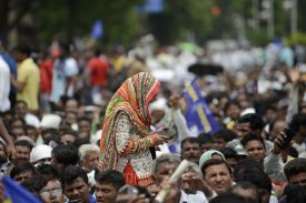 A woman in a headscarf walks amid a crowd of people.