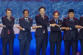 The five leaders, all wearing dark business suits and ties, stand in a line with their arms crossed over each other, each holding the hands of the men two either side of him.