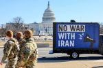 Three U.S. National Guard troops walk in front of a blue billboard truck that displays the message "No War With Iran" as it sits in front of the U.S. Capitol building.