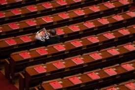 Red books are seen on the desks as a delegate reads a magazine before the closing session of the National People’s Congress in Beijing.