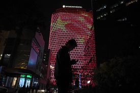 A man looks at his phone near a giant image of the Chinese flag on the side of a building in Beijing on Oct. 23, 2017.