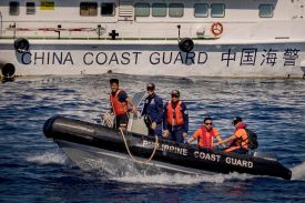 Philippine Coast Guard personnel sail past a China Coast Guard vessel during a resupply mission to troops stationed at Second Thomas Shoal in the South China Sea on March 5, 2024.