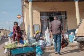 A vendor carries chickens for sale past fellow vendor at the Spice Market in Asmara, on October 4, 2025.