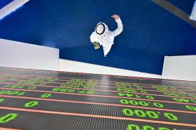 A trader walks beneath a stock display board at the Dubai stock exchange in the United Arab Emirates on March 8, 2020.