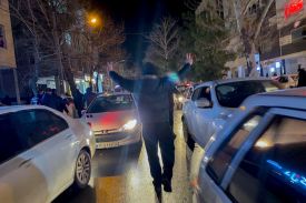 A protester flashes victory signs as traffic slows during demonstrations in Hamedan, Iran, on January 1, 2026.