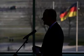 German Chancellor Friedrich Merz's silhouette is seen with the German national flag in the background as he delivers a speech during a New Year’s reception with relatives of soldiers and police personnel serving abroad, at the Chancellery in Berlin, Germany, on January 20, 2026.