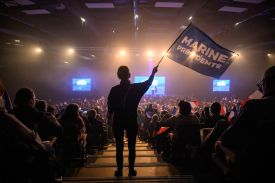 An attendee wave a flag prior to a rally of the French far-right Rassemblement National (RN) party candidate in Perpignan ahead of France's municipal elections in Perpignan, southern France, on February 28, 2026.