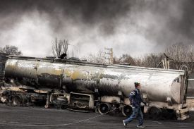 An Iranian civil defense member walks next to a destroyed fuel tanker following an overnight airstrike on the Shahran oil refinery in Tehran on March 8.