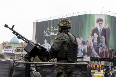 An Iranian security officer stands guard beneath a poster of Iran’s former leader, Ayatollah Ali Khamenei, in Tehran on March 10.