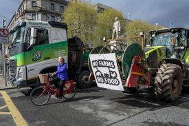 A woman cycles past tractors and trucks blocking O’Connell Street in the center of the city, as protests continue for a third day against the rising cost of fuel due to the Middle East crisis, in Dublin, Ireland.