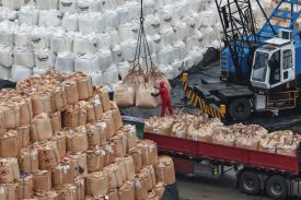A worker loads sulfur at a storage yard on a wharf in Nanjing, China.