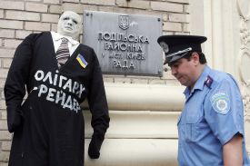 A policeman passes a doll symbolizing Ukrainian oligarch set by artists opposite the signboard of a district administration during the rally in Kiev, 12 July, 2007.