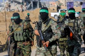 This image shows armed Hamas militants walking through Gaza. They are masked and wearing green headbands.