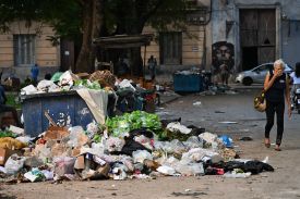 A woman covers her nose as she walks past garbage on a street in Havana, Cuba on Dec. 4, 2025.