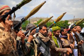 Supporters of the Houthis in Yemen are seen standing in line and holding weapons.