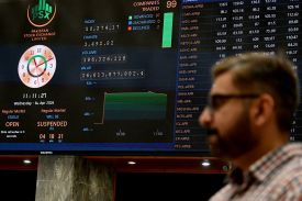 A stockbroker walks past share prices on a digital board during a trading session at the Pakistan Stock Exchange in Karachi.