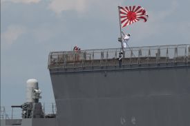 A sailor raises the Japan Maritime Self-Defense Force ensign on board the JS Ise, a Hyuga-class helicopter destroyer, as it docks at the international port in Manila, Philippines, on June 21, 2025.
