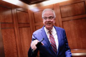 An animated U.S. Sen. Jerry Moran gestures with a cell phone in one hand as he speaks from inside an elevator in the U.S. Capitol.