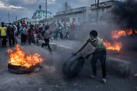A young protestor adds a tire to a burning barricade.