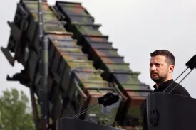 Ukrainian President Volodymyr Zelensky standing in front of a a Patriot missile defense system.