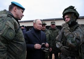 Putin stands among reservists in combat gear.