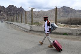 An Iranian refugee walks with his belongings after crossing the border from Iran to Armenia in the southern Armenian town of Meghri.