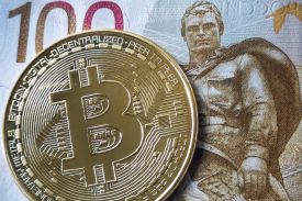 A souvenir bitcoin token is pictured with a 100 ruble bill in Moscow on July 30, 2024.