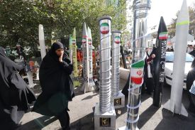 A woman walks past model missiles and centrifuges in Tehran.
