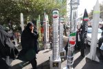 A woman walks past model missiles and centrifuges in Tehran.