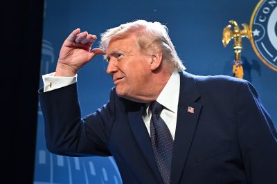 Trump is shown from the side as he peers ahead, with his hand shielding the top of his head.