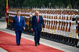 U.S. President Donald Trump and Chinese President Xi Jinping are seen walking past Chinese soldiers.