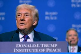 Donald Trump is seen sitting in front of a sign with his name with Steve Witkoff in the background.