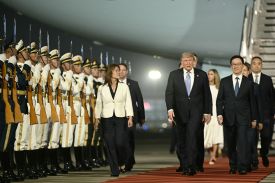 U.S. President Donald Trump is escorted by Chinese Vice President Han Zheng down a red carpet at Beijing Capital International Airport. A line of Chinese soldiers stand along the side.