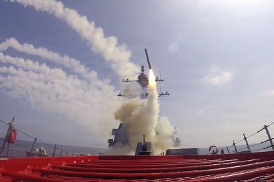 A missile fires from a military ship at sea.