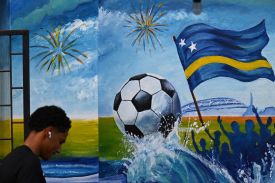 A man walks past a mural depicting a football and a flag of Curaçao in Willemstad, Curaçao, on April 10.