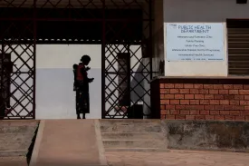 Woman and baby waiting outside a health clinic.